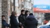 Місцеві жителі в окупованому Мелітополі Запорізької області поряд з банером «Росія – це розвиток», Україна, 13 лютого 2023 року