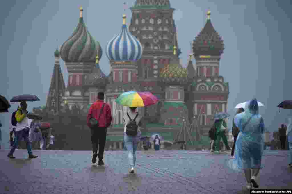 People walk through a rain shower on Red Square in Moscow.