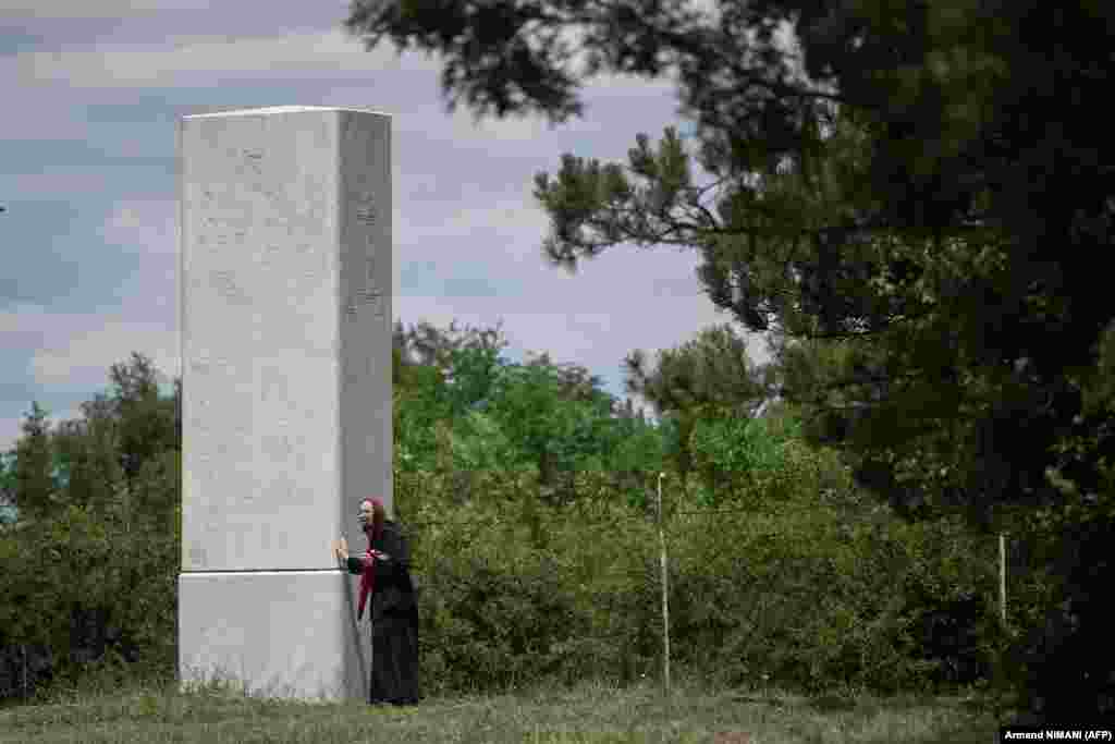 A Serb woman gestures next to a replica of the Gazimestan memorial.