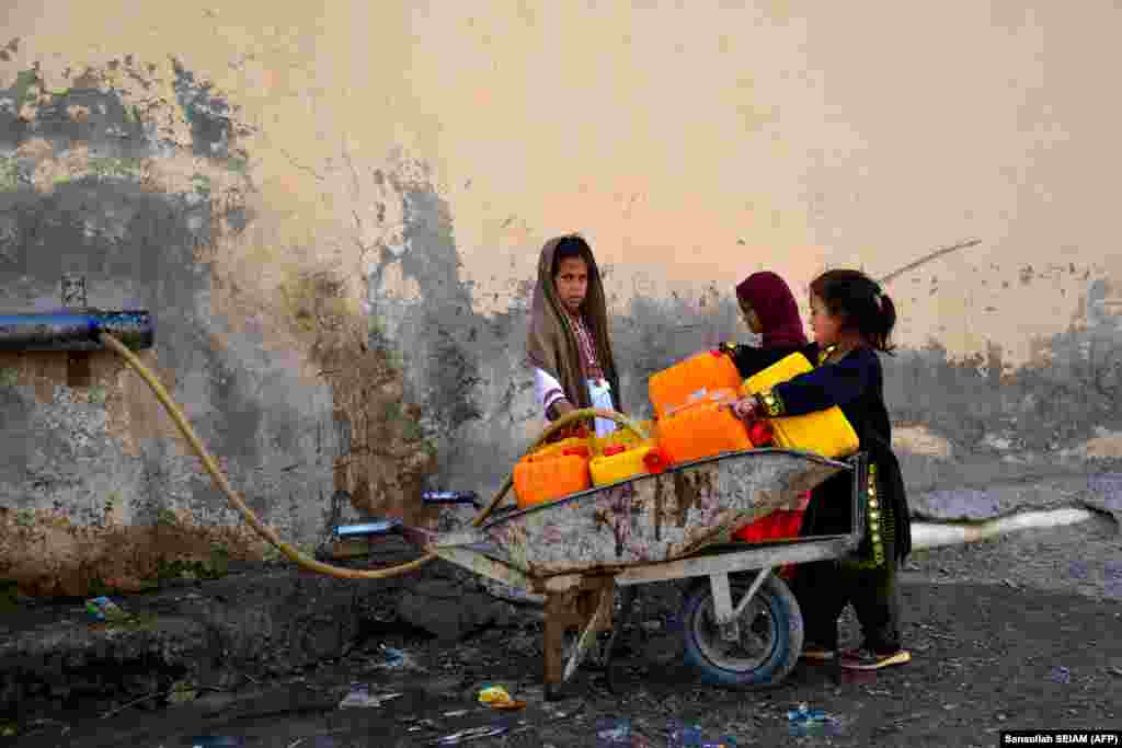 Afghan girls fill canisters with drinking water on the outskirts of Kandahar.