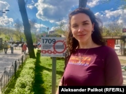 Valentyna Merzhyievska, the author of the Linguicide commemorative project, next to a memorial plate dedicated to anti-Ukrainian repressions.