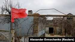 Червено знаме с избелял сърп и чук се вее над къщи в село Широкине в Донецка област, контролирано от Русия.