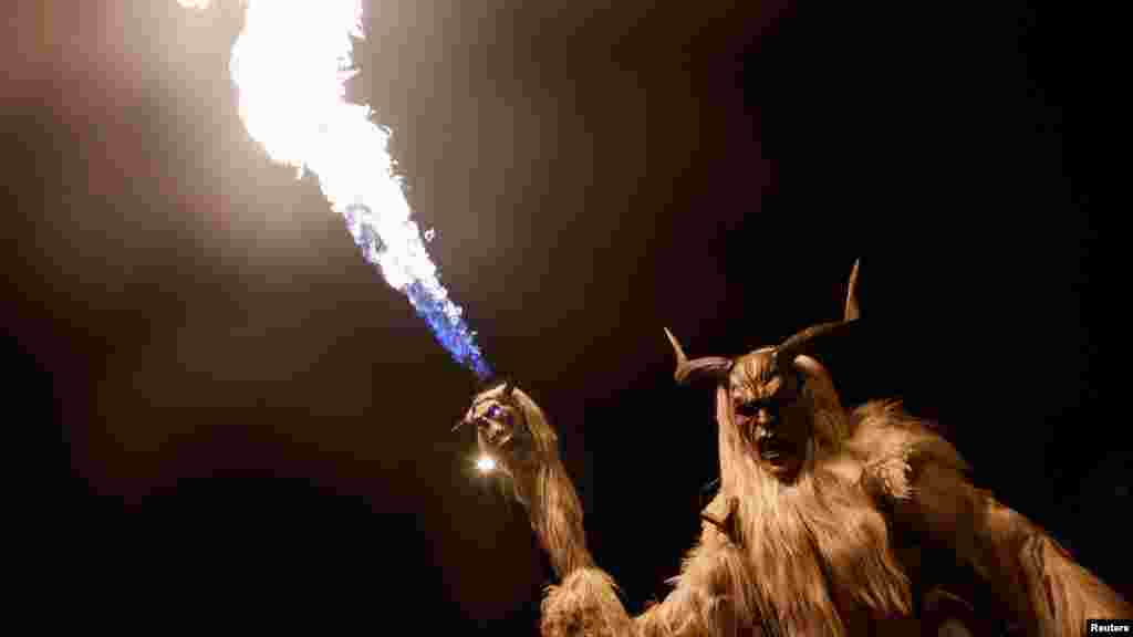 Osoba obučena kao rogati zli duh poznat kao &#39;Krampus&#39; paradira s bakljom kroz mali grad Goričane, Slovenija, 18. novembra.