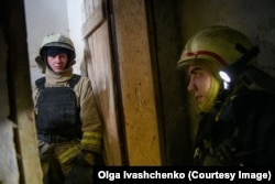 Emergency workers wait in a basement for an air-raid alert to end before continuing work at the site of an aerial bomb strike in central Kharkiv on April 7.