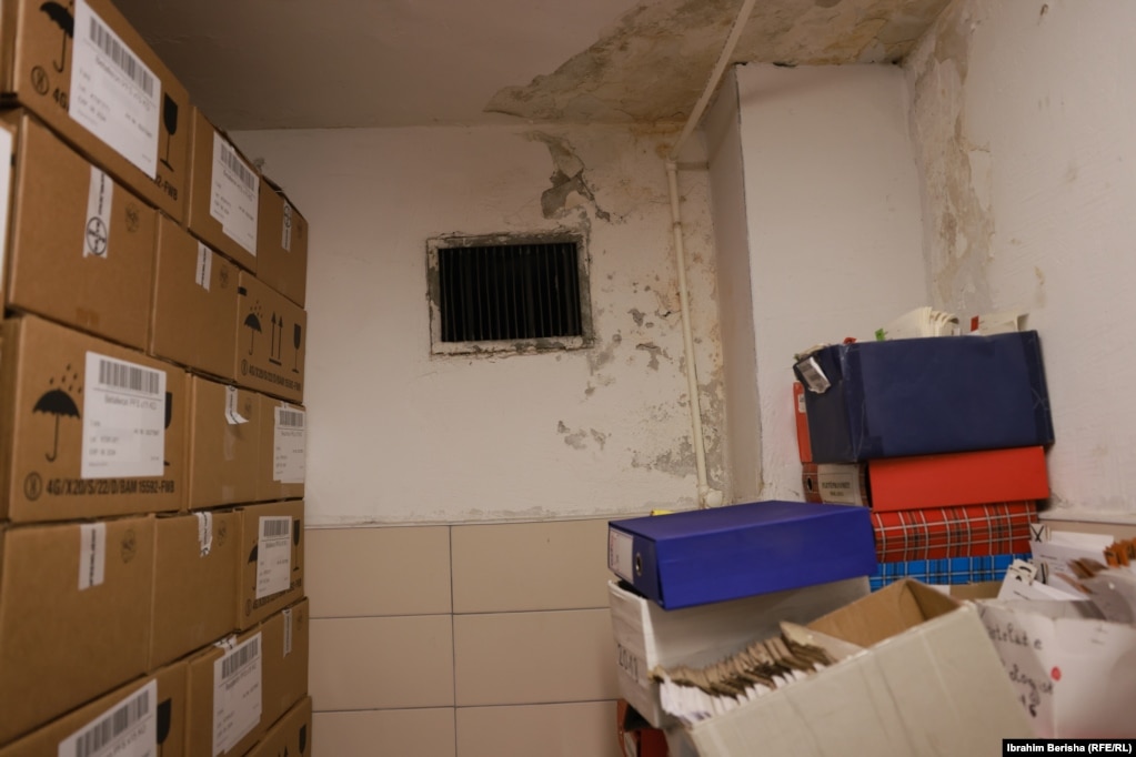 Një nga hapësirat në barnatoren qendrore të Qendrës Klinike Universitare të Kosovës, ku janë të vendosura barnat dhe dokumentet.  Aty shihen muri dhe tavani i dëmtuar nga lagështia dhe rrjedhja e ujit. 