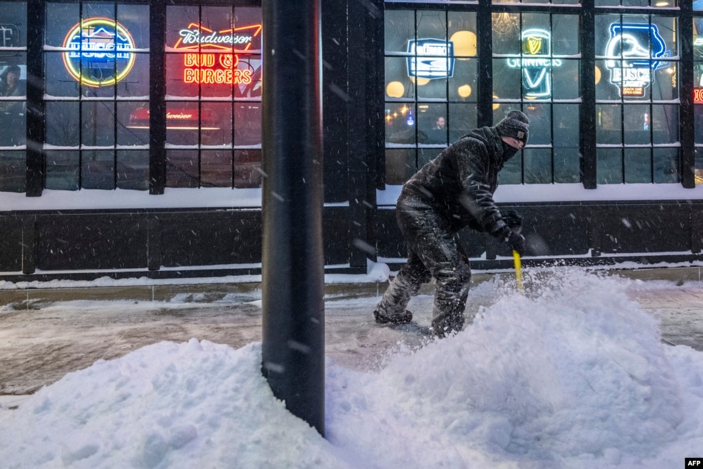 Një burrë duke hequr borën me lopatë.