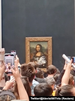 Posjetitelji fotografiraju i vide sliku "Mona Lisa" nakon što je torta razmazana na zaštitnom staklu, 29. maj 2022.