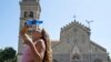 Дівчина виливає пляшку води собі на голову на острові Сицилія, під час спеки. Італія, 16 липня 2023 року