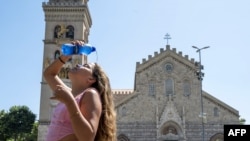 Një vajzë hedh ujë në fytyrën pranë një kishe në qendër të Mesinës, në Sicili, më 16 korrik 2023.