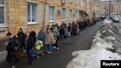 Oamenii stau la coadă pentru a intra într-o secție de votare în jurul orei 12, când are loc acțiunea „Amiază împotriva lui Putin”, acțiune promovată de Alexei Navalnîi și susținută de opoziția rusă. Moscova, 17 martie 2024.