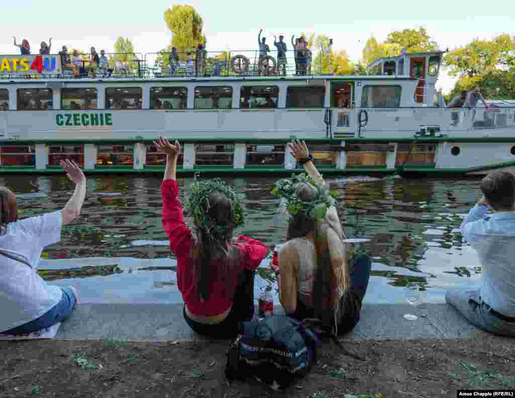 Ukrainian girls wave at a passing tourist boat during the Ivan Kupala event. Natalia Vesela, a Ukrainian who has lived in the Czech Republic since 2003, organized the Ivan Kupala festival and is behind several other events held for Ukrainians in Prague. &quot;When [Russia&rsquo;s full-scale invasion] began, I started thinking, &#39;How can I help, why am I just sitting on my ass in bed?&#39;&quot; she told RFE/RL.