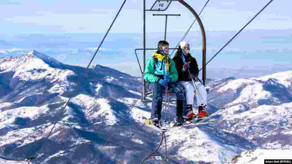 Vizitorët në teleferik duke shijuar pamjet e bukura të maleve të mbuluara me borë.