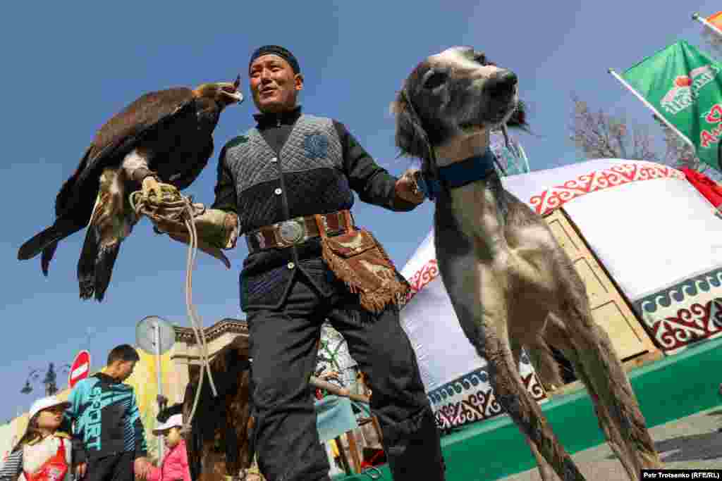 Мужчина с беркутом и собакой казахской породы тазы приглашает прохожих сфотографироваться с животными&nbsp;