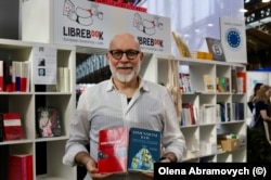 Антоніо Пароді, власник інтернаціонального книжкового магазину Libre Book, демонструє книги про Київ: від Андрія Куркова та антологію зі згадками про столицю від українських та іноземних письменників