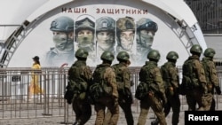 Soldați ruși la o expoziție care prezintă vehicule blindate și echipamente capturate de la forțele ucrainene, la muzeul în aer liber Victory Park din Moscova, Rusia, 31 mai 2024.