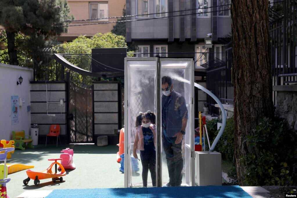 Një burrë iranian dhe vajza e tij dezinfektohen përpara se të hyjnë në kopshtin e fëmijëve, në Teheran, Iran, 19 tetor 2020. Fotografia e bërë më 19 tetor 2020.
