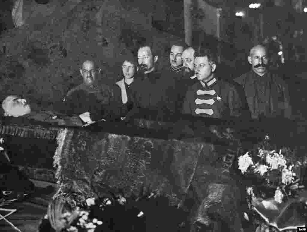 Bolșevici de rang înalt, inclusiv Feliks Dzerjinski (al treilea din stânga) - faimosul fondator al poliției secrete sovietice care a pus la cale și executat multe dintre crimele în masă comise de bolșevici - se reculeg la catafalcul lui Lenin, la sfârșitul lunii ianuarie 1924. După moartea lui Lenin, s-a declanșat o intensă dezbatere despre ce trebuie făcut cu cadavrul fostului lider bolșevic. Stalin a făcut presiuni pentru ca trupul să fie îmbălsămat și expus în public, spunând că această conservare &bdquo;nu ar contraveni vechilor obiceiuri rusești&rdquo;. Lev Troțki, alt lider bolșevic, a respins ideea de a transforma trupul unui revoluționar ateu în moaștele unui sfânt. Expunerea cadavrului pentru a fi venerat de populație &bdquo;nu ar avea nimic de-a face cu știința marxismului&quot;, a protestat el.
