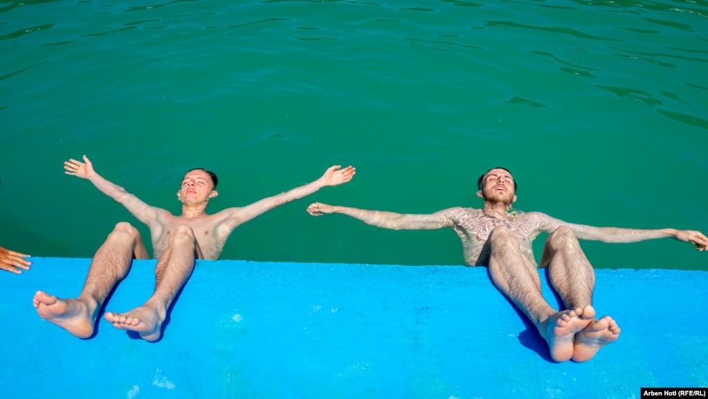 Dy djem duke i shijuar rrezet e diellit buzë pishinën në Prishtinë. 18 korrik 2023.