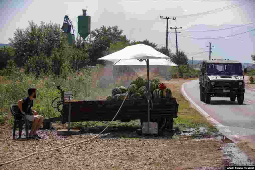 A vendor sprays watermelons with mist during a heat wave in the village of Krushe, Kosovo.