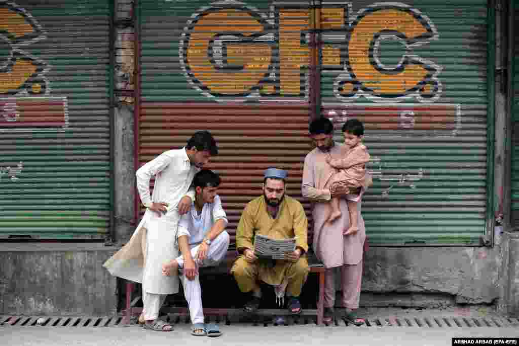 People read a newspaper in front of closed market stalls after traders called for a shutter-down strike to protest against inflation in Peshawar, Pakistan.