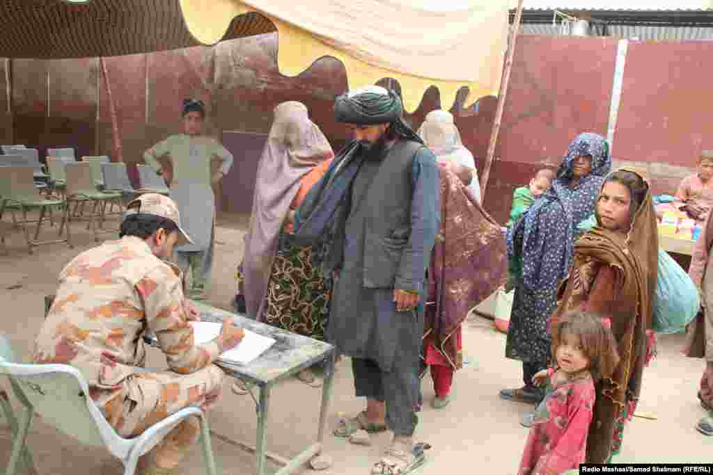 An official checks the documents of an Afghan family.