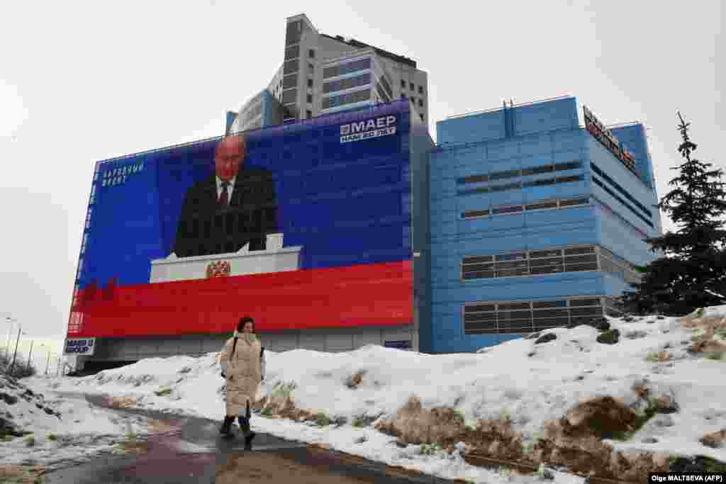 A woman in Moscow walks past a screen displaying a broadcast of Russian President Vladimir Putin&#39;s annual state-of-the-nation address on February 29.&nbsp;