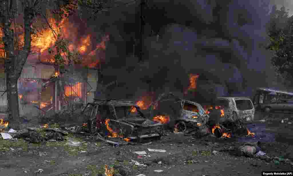 Un cadavru zăcând printre mașinile și piața incendiate în urma atacului cu rachete.