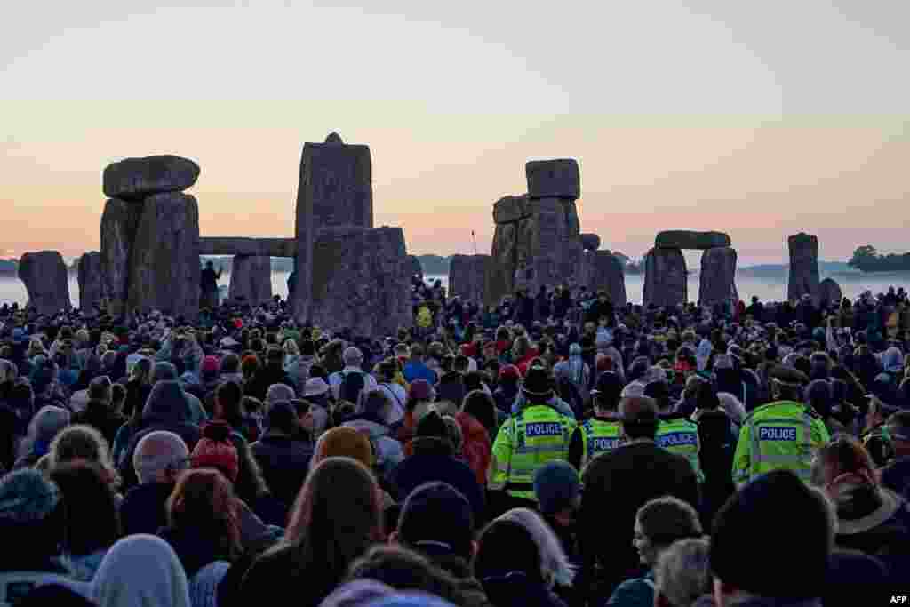 Oficerët e policisë qëndrojnë mes njerëzve që festojnë lindjen e diellit në Stonehenge, më 21 qershor 2024, gjatë Festivalit të Solsticit Veror, i cili daton mijëra vjet më parë, duke festuar ditën më të gjatë të vitit. Monumenti prej guri - i gdhendur dhe i ndërtuar në një kohë kur nuk kishte mjete metalike - simbolizon periudhën parahistorike gjysmë mitike të Britanisë prej nga kanë lindur legjenda të panumërta.