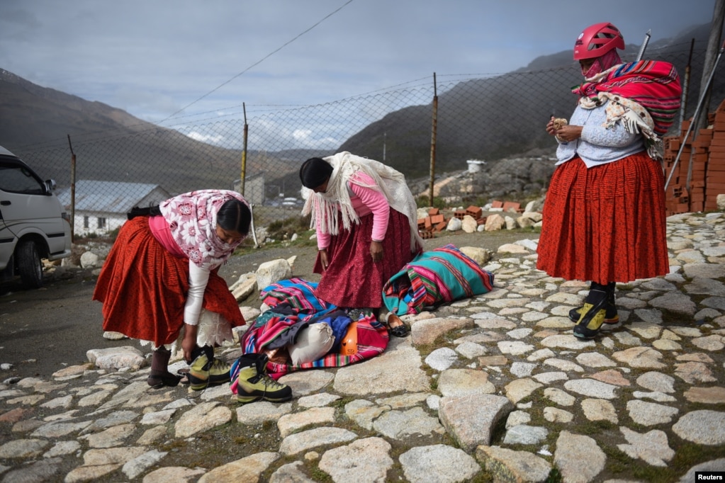 Gratë e reja shihen teksa përgatiten për t&#39;u ngjitur në malin Huayna Potosi.&nbsp;Veshje tradicionale e vajzave të reja që njihen si &quot;cholita&quot;, janë fundet e kuqe të ndezura.