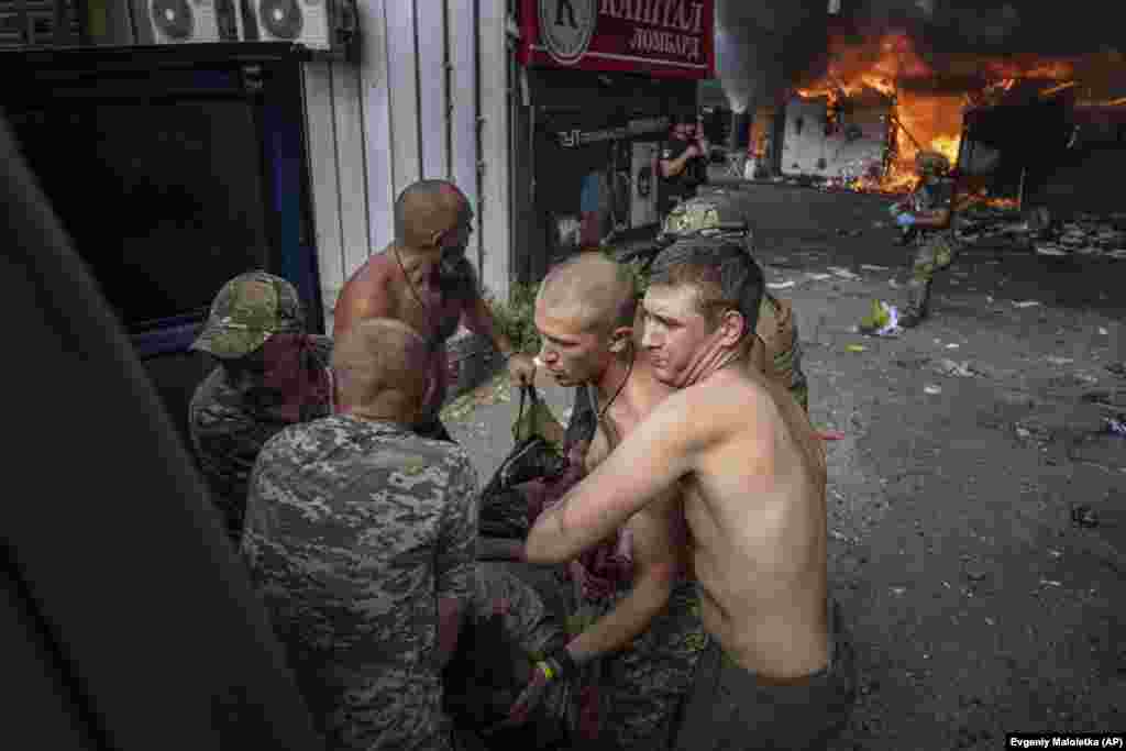 Ukrainian soldiers carry an injured woman to an ambulance.