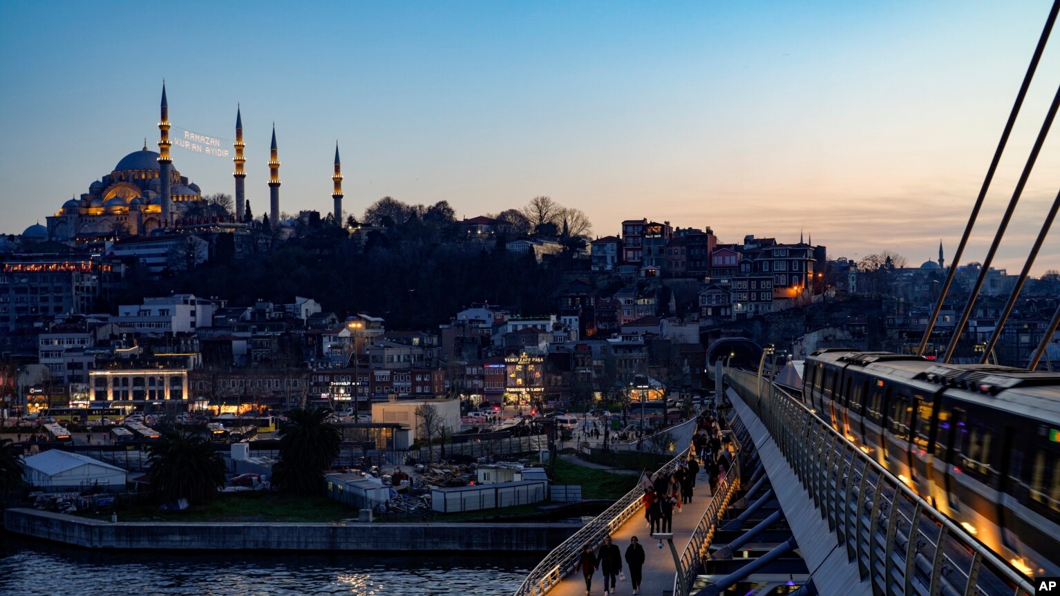 Xhamia Sulejman shihet lart, ndërsa poshtë shihen këmbësorët teksa ecin përgjatë urës së metrosë, Halic, Stamboll, 10 mars 2024.
