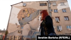 Lebibe Topalli duke kaluar pranë muralit që ka pikturuar vetë në Ferizaj.