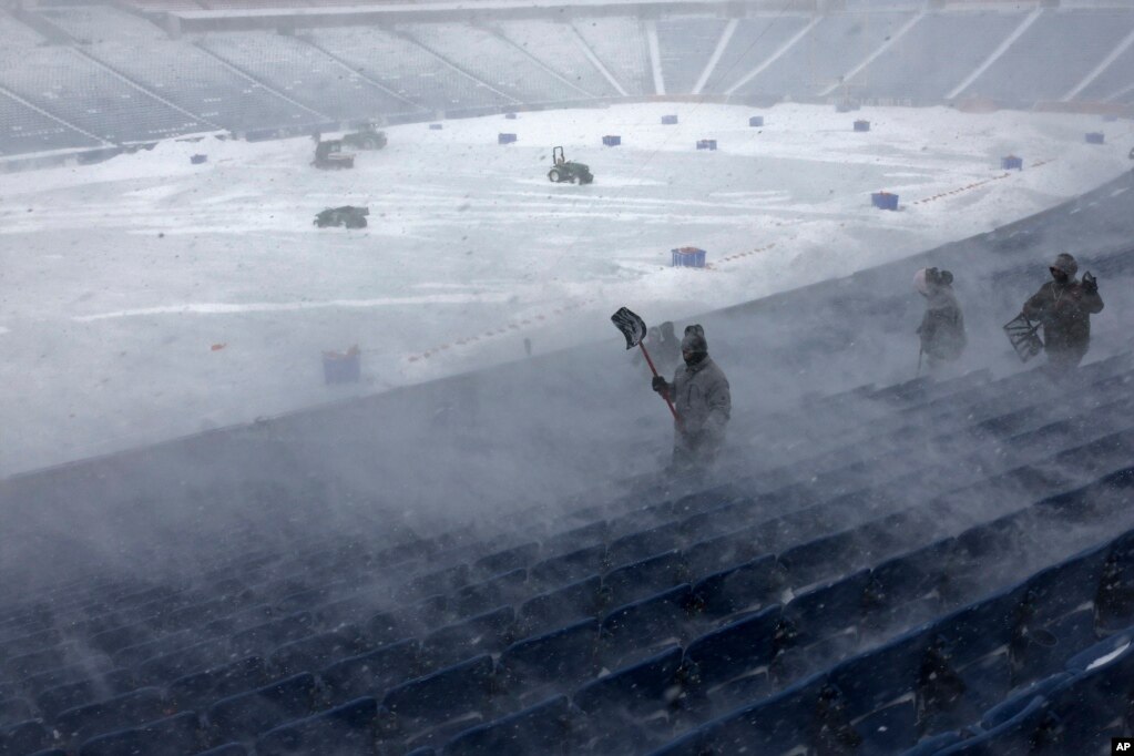 Punëtorët duke hequr borën nga stadiumi Highmark në Nju Jork të dielën e 14 janarit 2024. Një stuhi bore potencialisht e rrezikshme që goditi rajonin e Buffalos të shtunën, bëri që të anulohet një ndeshje e planifikuar.
