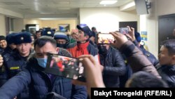 Журналист Сайпидин Султаналиевди милиция кызматкерлери сотко алып келүүдө. 17-январь. 