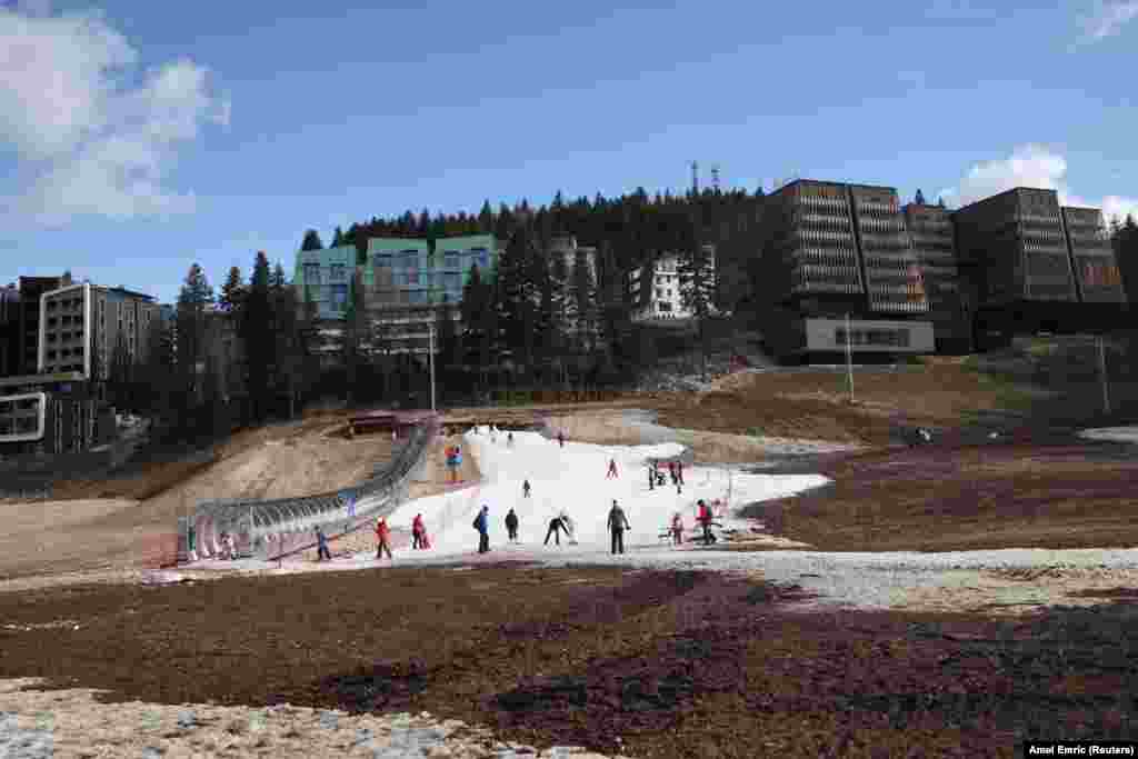 Visitors walk on the remaining traces of snow mixed with mud during Bosnia&#39;s unseasonably warm weather on Mt. Bjelasnica, a popular ski resort near Sarajevo.