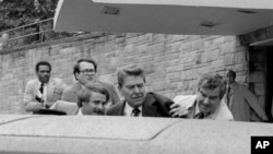 Agenții Serviciului Secret îl împing pe președintele Ronald Reagan într-o mașină după ce este rănit la Washington, D.C., 30 martie 1981.