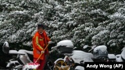 Një punonjës i qytetit pastron shtegun e mbuluar me borë, pasi një reshje dëbore goditi kryeqytetin e Kinës, Pekinin, më 11 dhjetor 2023.