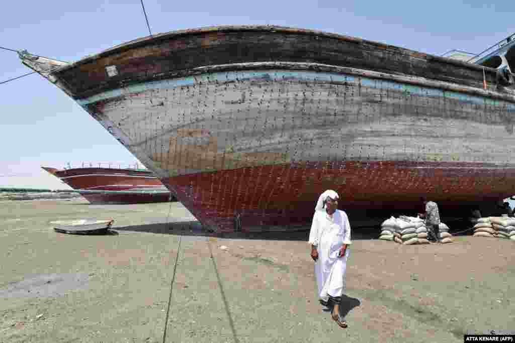 Мужчина на фоне традиционной иранской лодки (ленджа), ожидающей реставрации на&nbsp; острове Кешм, 29 апреля. Силуэты этих деревянных судов ручной работы &mdash; такая же часть морского пейзажа Ближнего Востока, как и пейзажи с парусными дау на Аравийском полуострове &nbsp; 