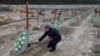 Bucha Deputy Mayor Serhiy Shepetko places flowers on graves of unidentified people killed by Russian soldiers during the occupation of the town outside Kyiv at the town's cemetery in February 2023.