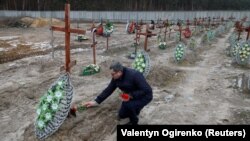 Bucha Deputy Mayor Serhiy Shepetko places flowers on graves of unidentified people killed by Russian soldiers during the occupation of the town outside Kyiv at the town's cemetery in February 2023.