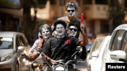 Момчета с боядисани лица карат мотоциклет по време на честването на древния индийски празник "Холи" в Мумбай, Индия, 25 март 2024 г.