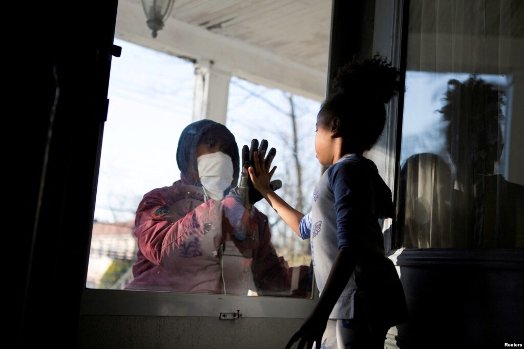 Hashim, një punëtor thelbësor në fushën e kujdesit shëndetësor, përshëndet vajzën e tij përmes derës së mbyllur ndërsa ruan distancën sociale nga familja e tij ndërsa punon në mes të shpërthimit të sëmundjes së koronavirusit COVID-19 në New Rochelle, Nju Jork, SHBA, 11 Prill, 2020.&nbsp;