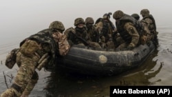 Группа украинских морских пехотинцев отплывает от берега Днепра на передовой под Херсоном, 14 октября 2023