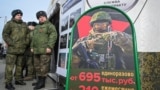 Russian soldiers stand near a mobile recruiting center with a board containing information about payments in Rostov-on-Don, Russia.