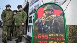 Russian soldiers stand near a mobile recruiting center with a board containing information about payments in Rostov-on-Don, Russia.
