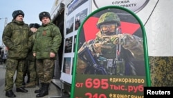Ushtarët rusë qëndrojnë pranë një qendre të lëvizshme rekrutimi me një bord që përmban të dhëna për pagesat në Rostov-on-Don, Rusi.