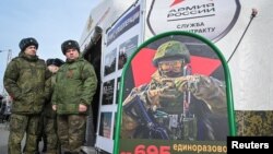 Ruski vojnici stoje u blizini mobilnog regrutnog centra s informativnim posterom o platama u Rostovu na Donu u Rusiji, mart 2024.