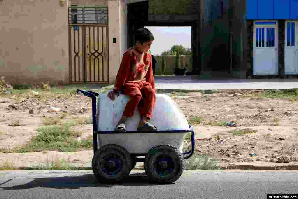 An Afghan boy sits on his cart of ice creams as he waits for customers along a street in Herat.