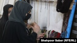 دو تن از دختران دانش آموز در هرات که در کارگاه قالین بافی کار می کنند
