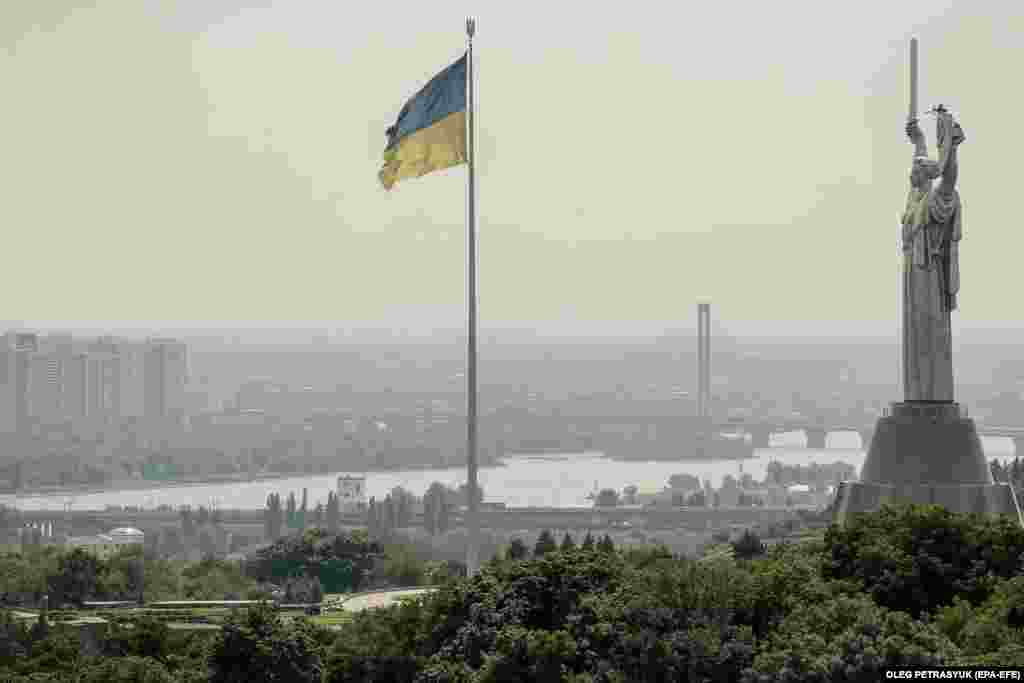 The Ukrainian flag flies next to the Motherland Monument in Kyiv.